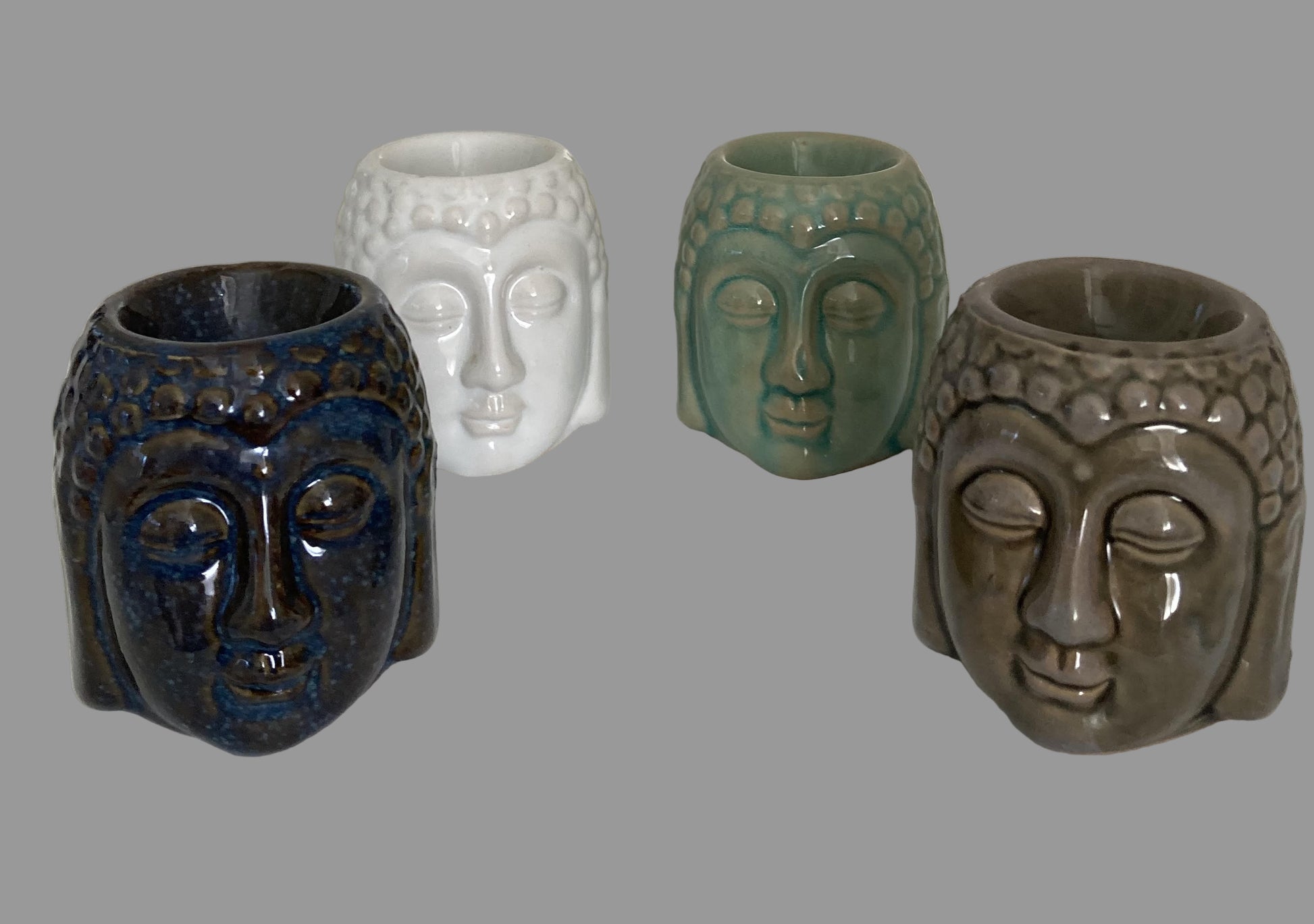 Four ceramic face-shaped vases on a white surface with a light gray background